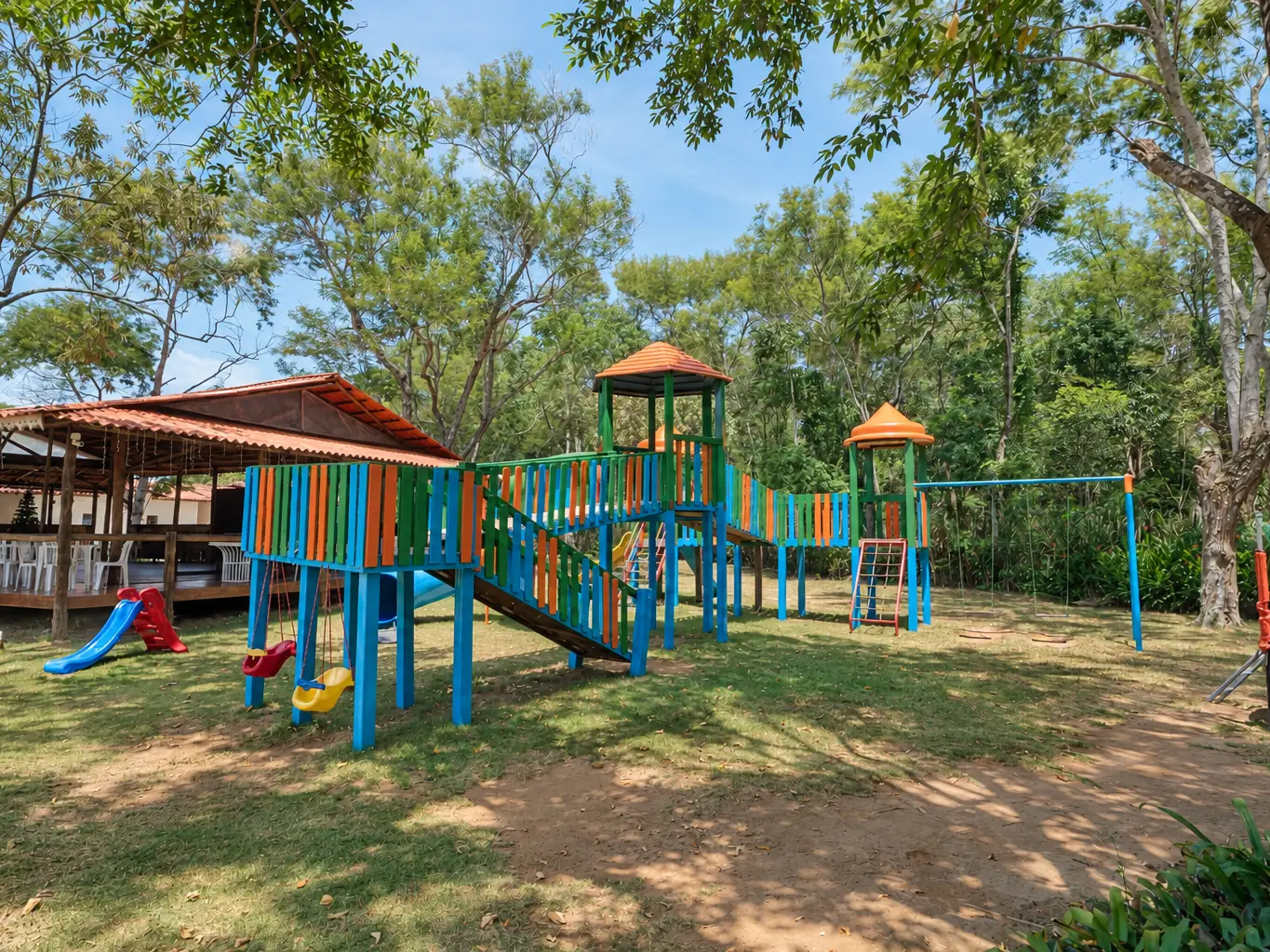 Playground do Acquamarine Park Hotel com escorregador e brinquedos no gramado