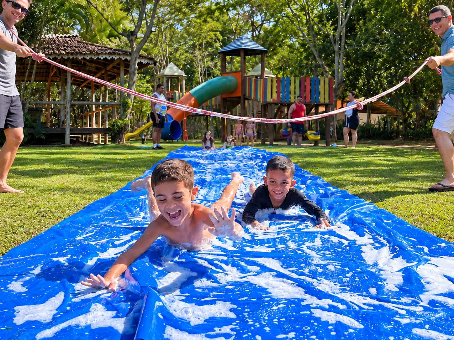 Recreadores conduzindo o tobo-lona com crianças no gramado do Acquamarine Park Hotel