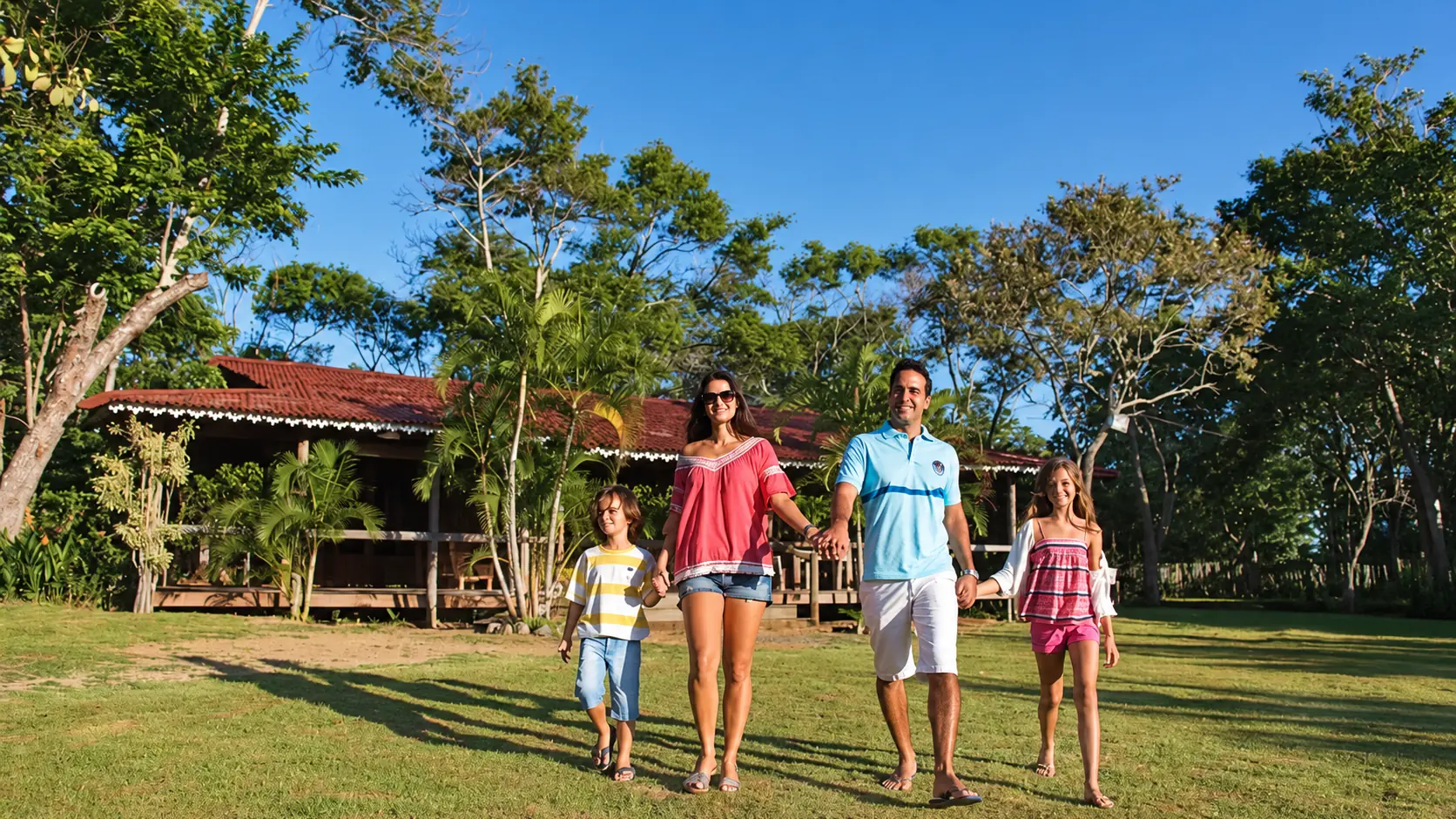 Família caminhando de mãos dadas no gramado do Acquamarine Park Hotel